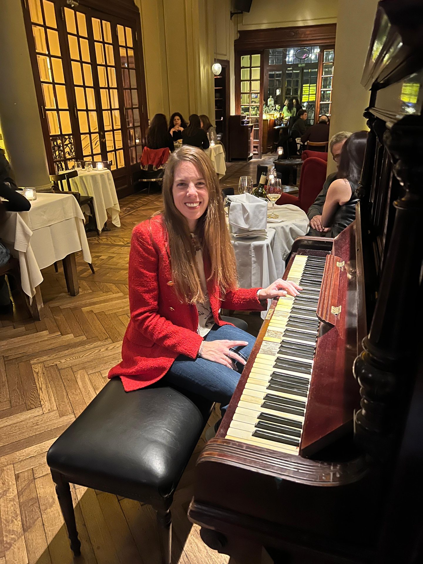 Pilar sonríe al piano, con blazer rojo, en Million Piano session
